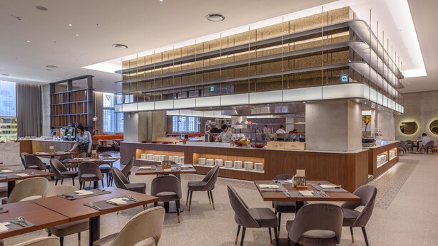 A modern restaurant with a central counter, multiple dining tables, and chairs. - Avani Central Busan (Busan)