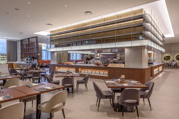 A modern restaurant with a central counter, multiple dining tables, and chairs. - Avani Central Busan (Busan)