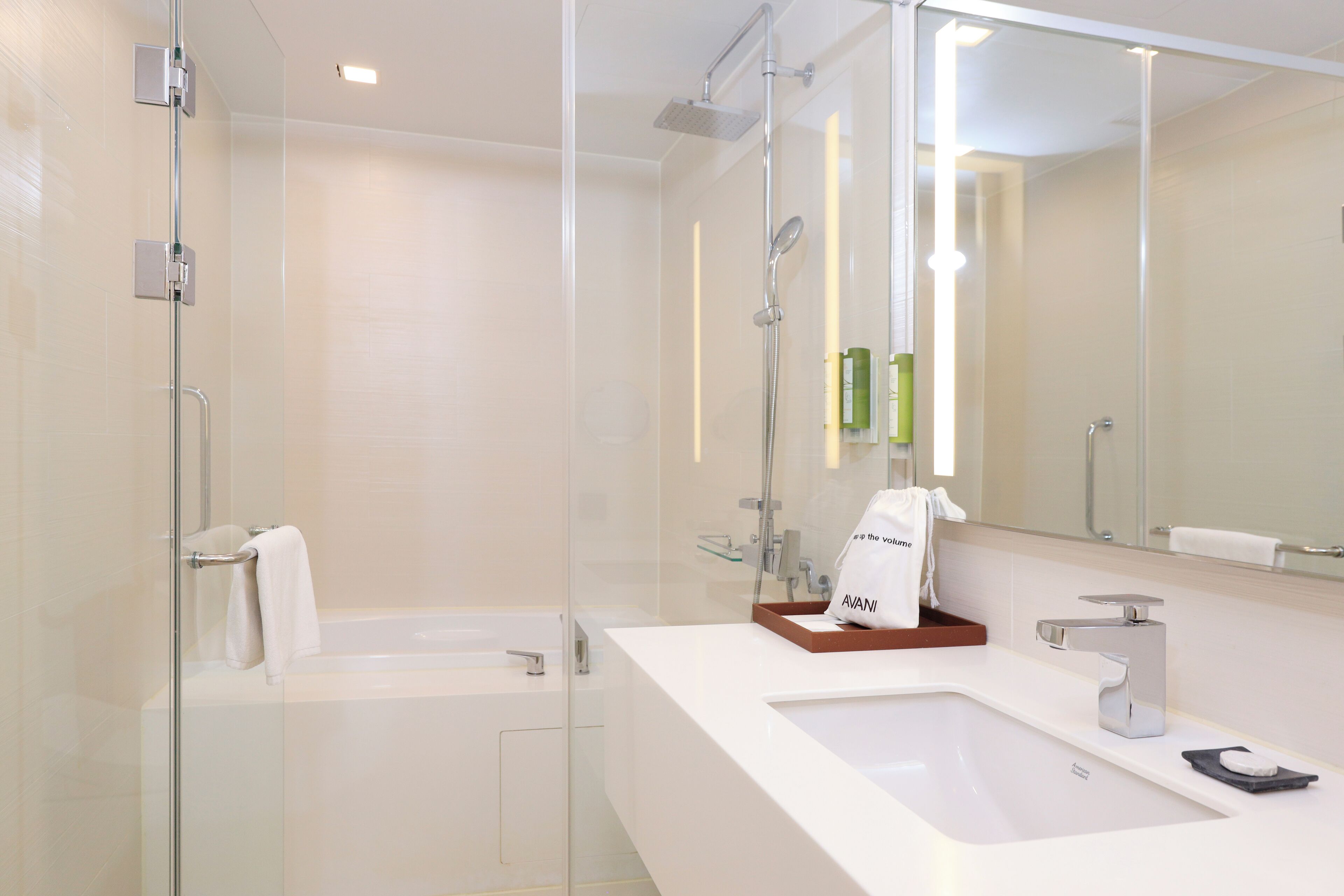 Un baño moderno con ducha de vidrio, lavamanos blanco y un espejo grande.
