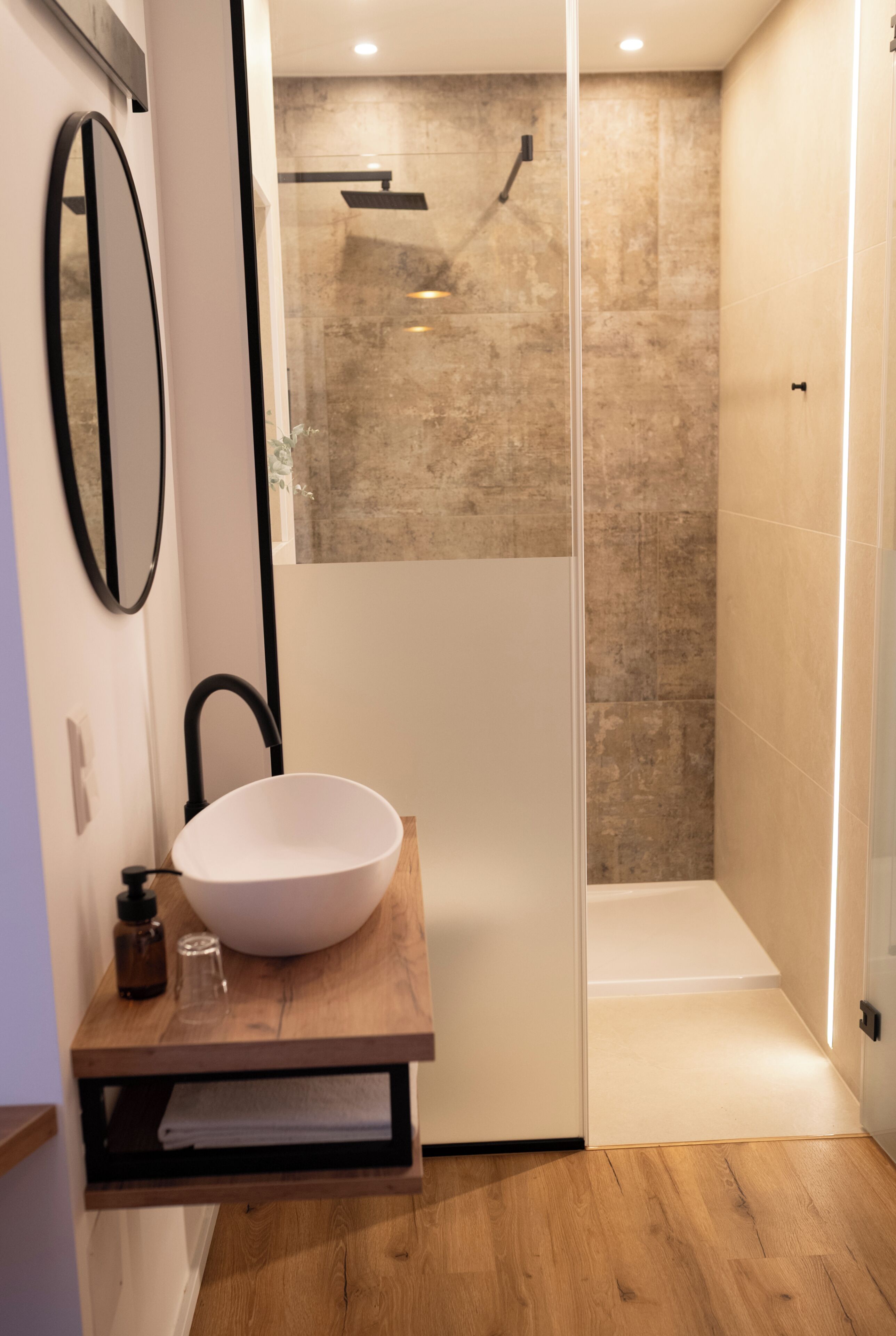 Une salle de bain moderne avec un grand lavabo blanc, un miroir et un espace douche.