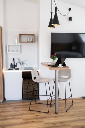 A modern kitchen with a wooden countertop, two chairs, a TV, and pendant lights. - Hotelmaria (Gramatneusiedl)