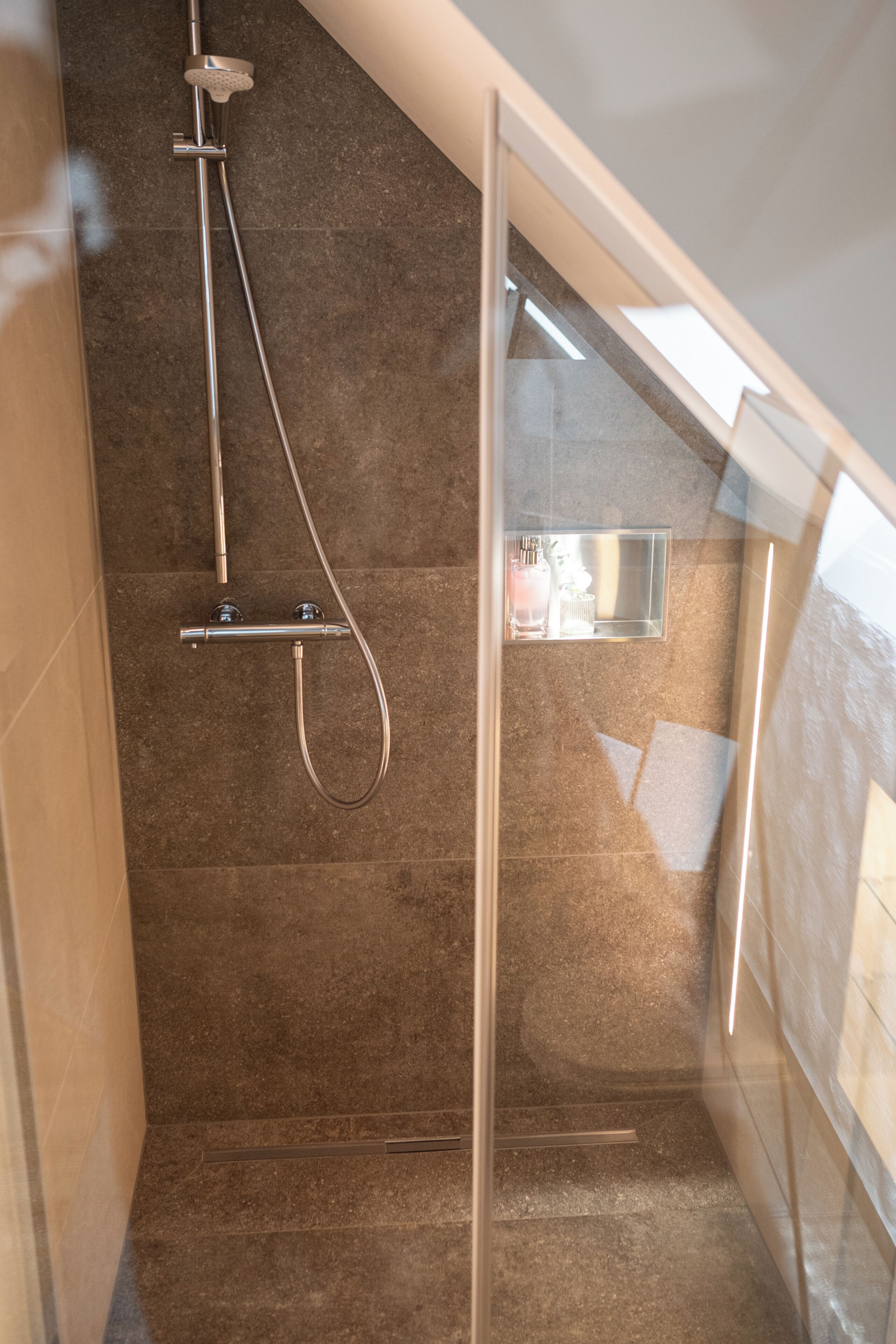 A shower with a glass door, a visible towel rack, and a small window.