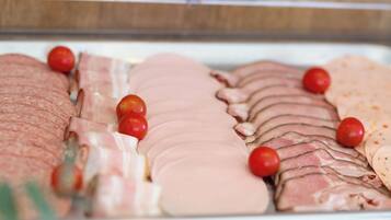 A display of sliced meats and tomatoes in a refrigerated case.