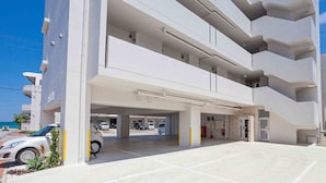 Un edificio de varios pisos con garaje, paredes exteriores blancas y cielo despejado.