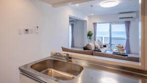 Una cocina moderna con un lavamanos de acero inoxidable, un horno empotrado y un amplio ventanal con vistas al mar.