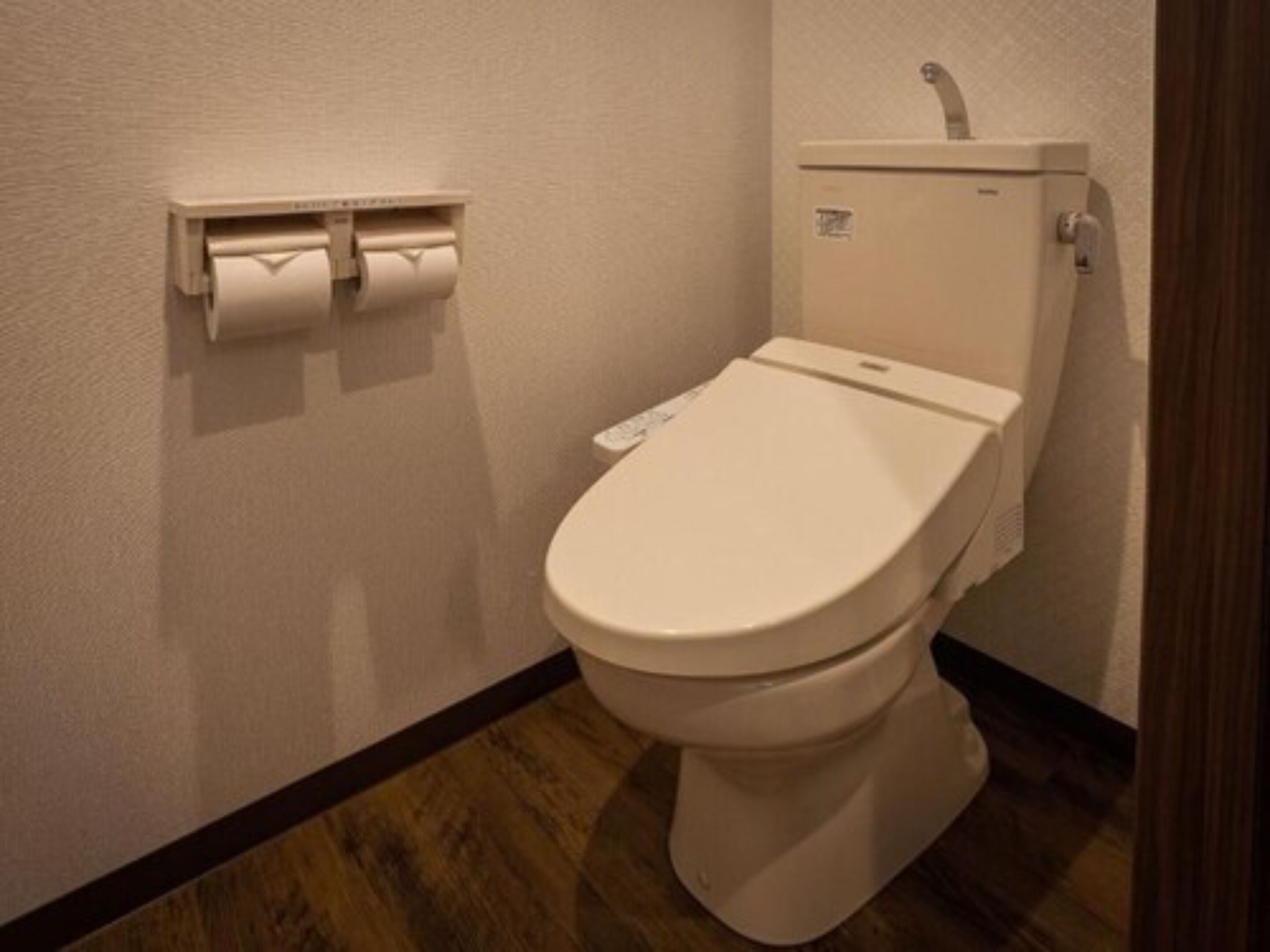 A standard white toilet with a paper towel dispenser on the wall.