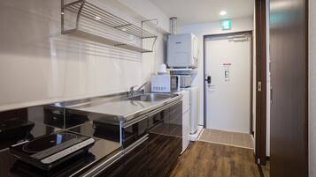 Una cocina moderna con encimera de acero inoxidable, microondas integrado y refrigerador.