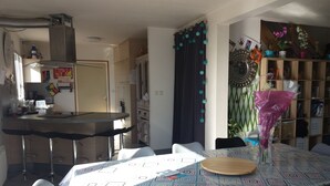 Un espace repas agrémenté d’une nappe à motifs, de tabourets de bar et d’un élément décoratif central.