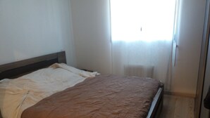 Une chambre à coucher avec un lit, un plancher en bois et une fenêtre avec des rideaux.