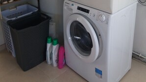 Un appareil combiné lave-linge et sèche-linge, avec une étagère au-dessus pour ranger divers objets.
