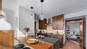 Una cocina moderna con una isla central, armarios de madera e iluminación colgante.