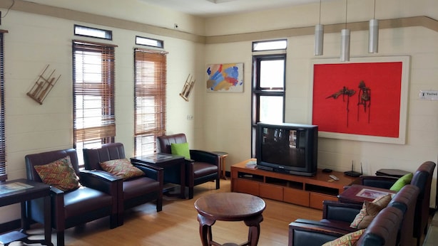 A spacious living room with leather sofas, a wooden coffee table, and a television. - Rumah Tawa Guesthouse 1 (Bandung)