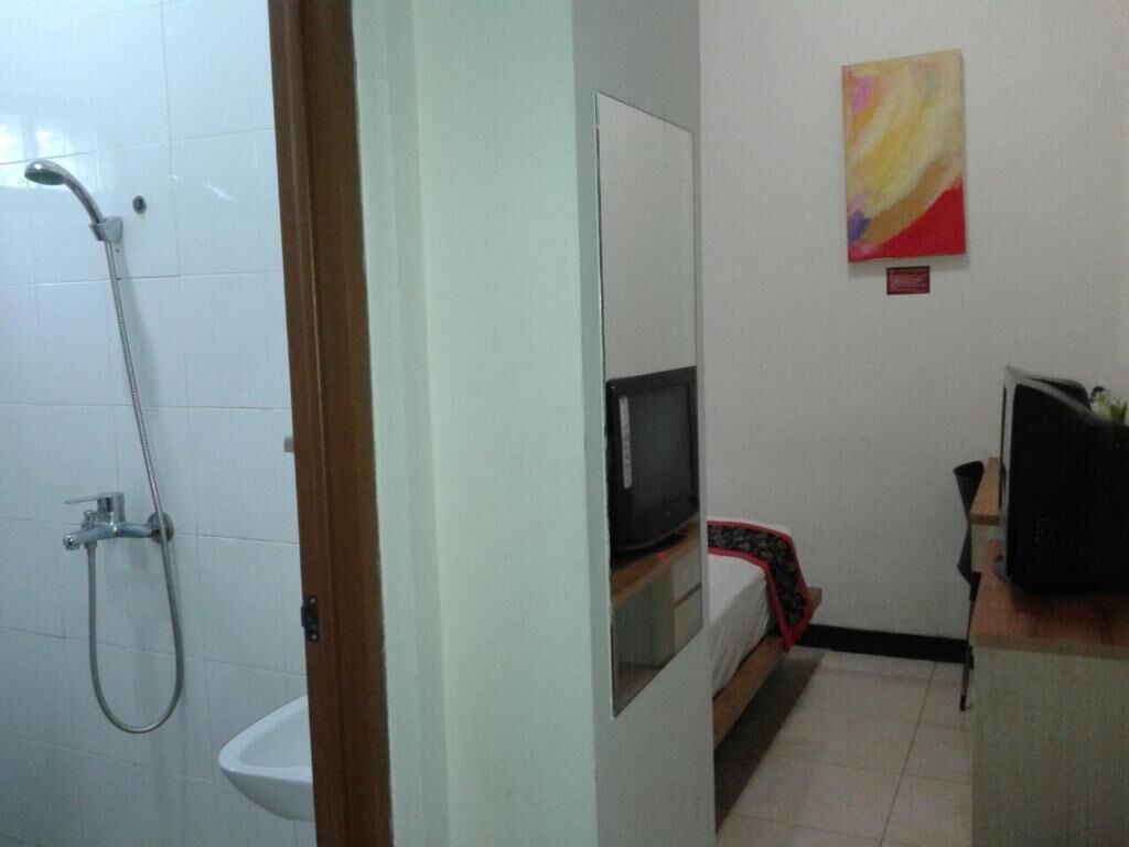 A bathroom with a shower, sink, and a bed with a TV.