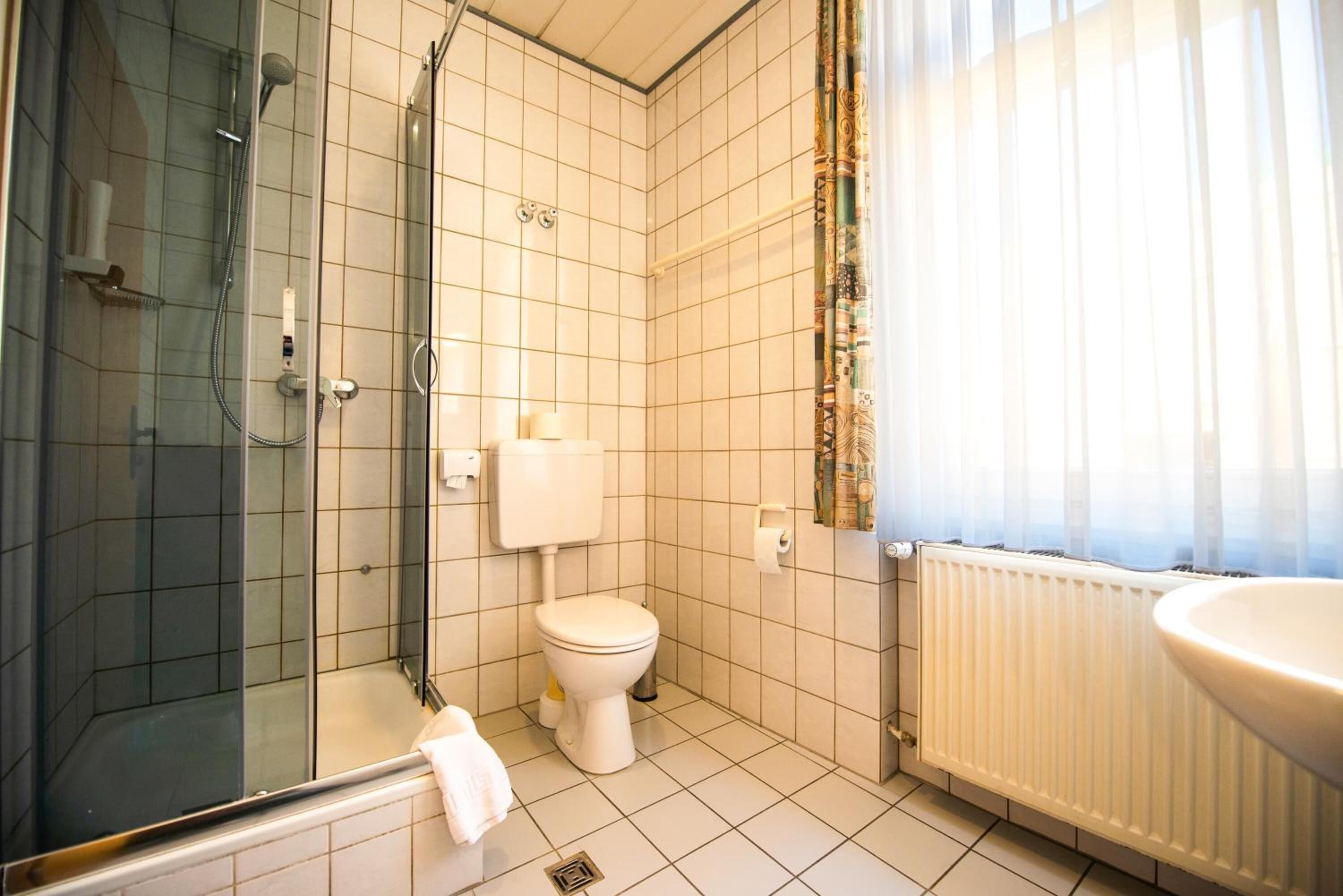 Un baño con ducha separada por mampara de vidrio, inodoro y lavabo.