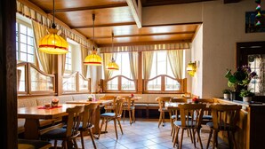 Een restaurant met houten meubels, grote ramen en hangende lampen.