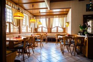 Un restaurante con mobiliario de madera, ventanas amplias y lámparas colgantes.
