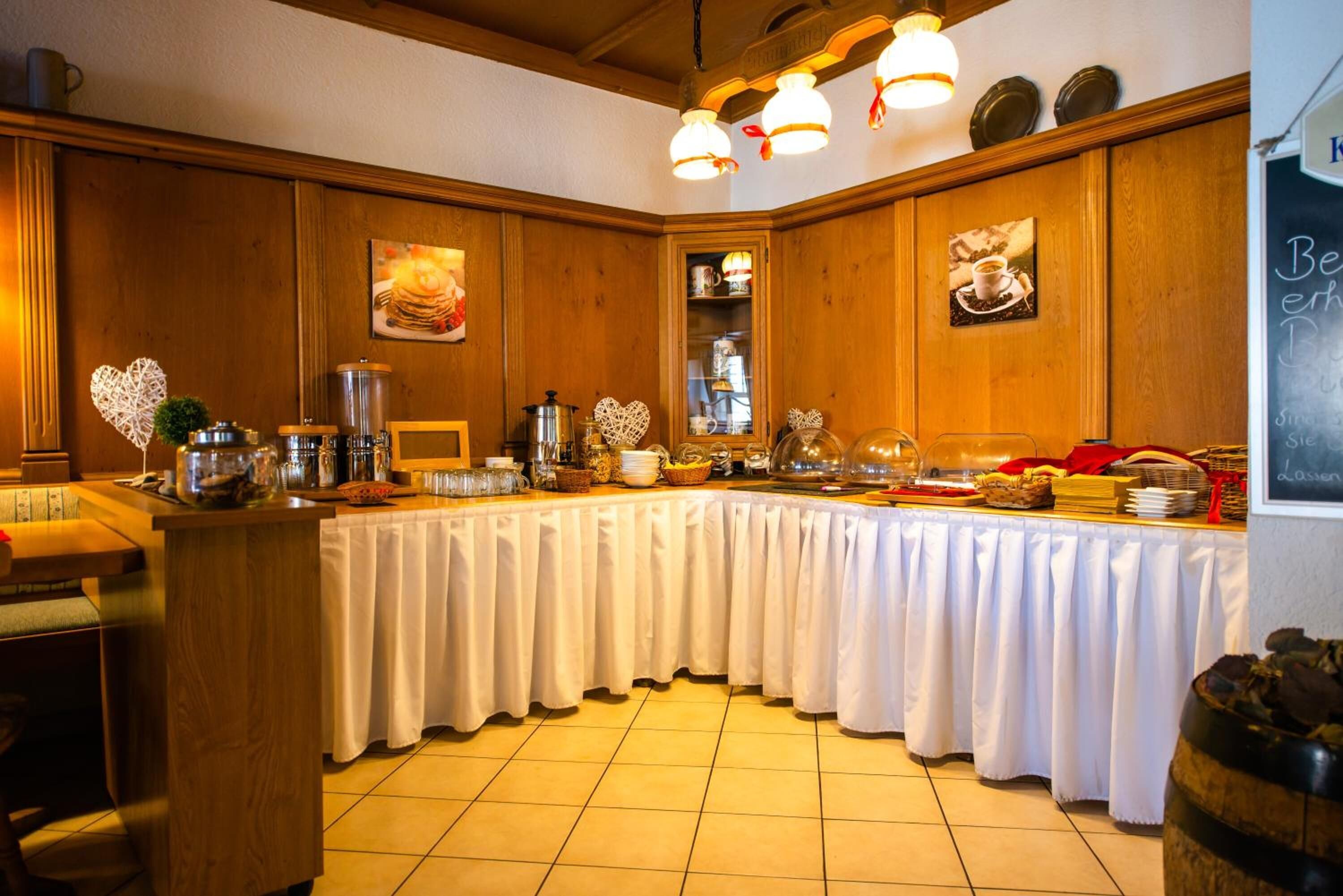 A buffet setup with a long table covered in white cloth, surrounded by wooden paneling and decorated with heart-shaped ornaments.
