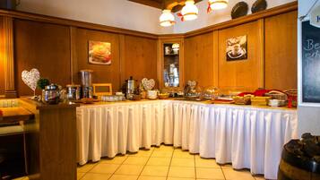 A buffet setup with a long table covered in white cloth, surrounded by wooden paneling and decorated with heart-shaped ornaments.