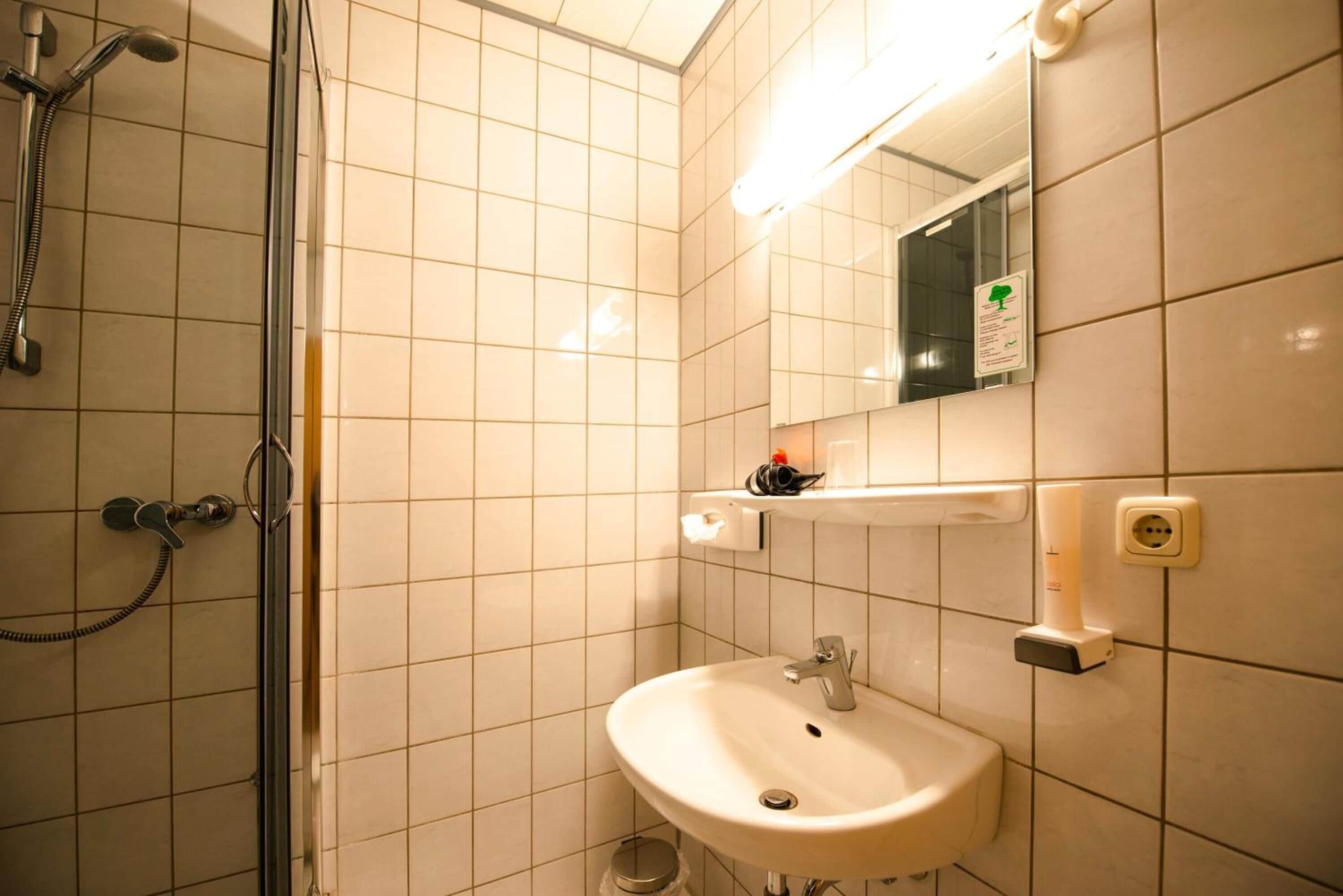 A bathroom with a shower, sink, and mirror.
