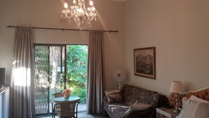 Um quarto com um candelabro, um sofá, uma televisão, um ventilador e um quadro.