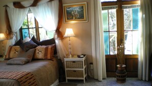 Quarto com cama, mesas de cabeceira, abajur, tapete e janela com cortinas.