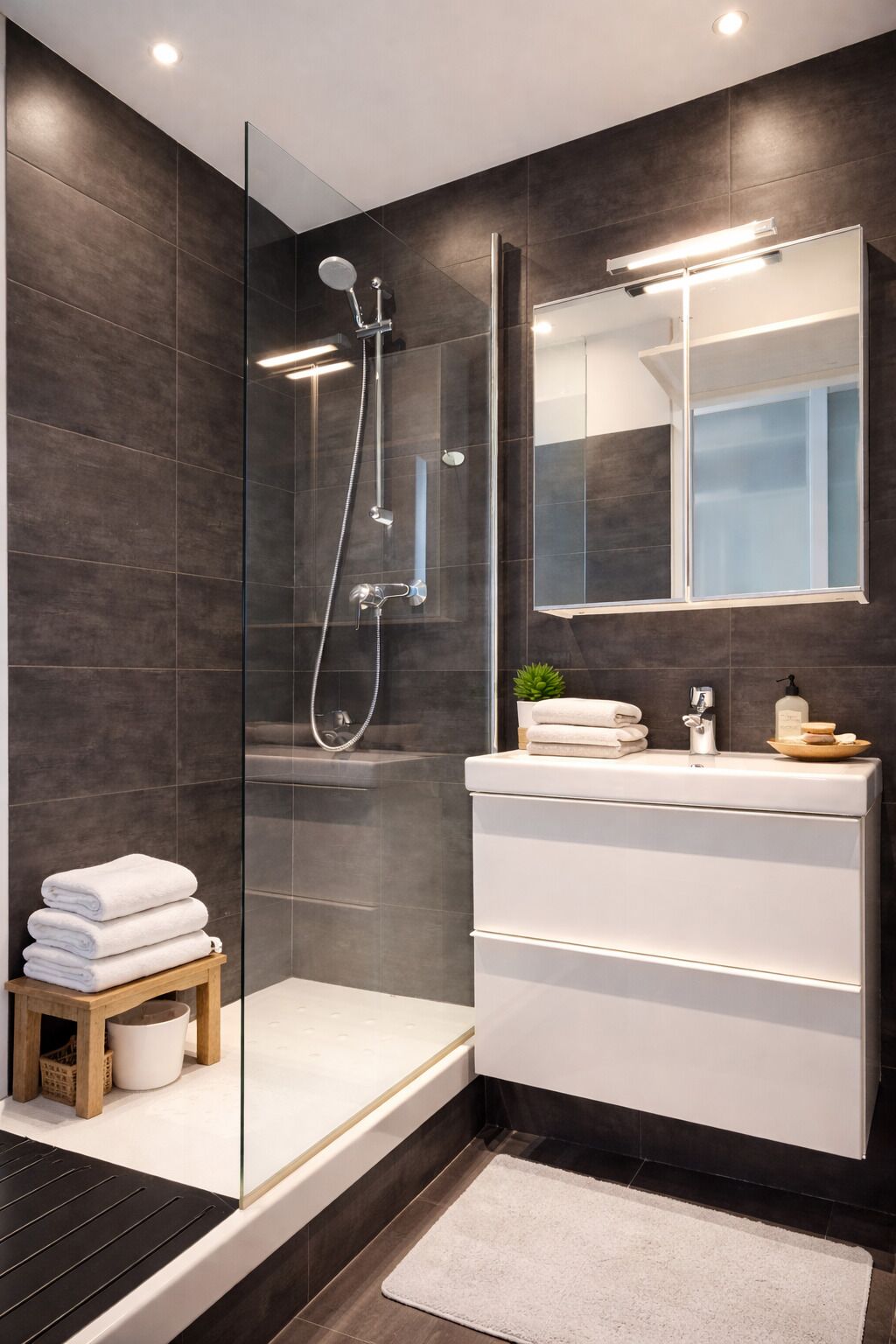 A modern bathroom with a glass shower enclosure, a white vanity with a mirror, and a small plant on the counter.