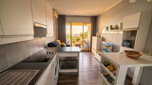 A compact kitchen with a built-in oven, a washing machine, and a dining area with a view. - F2 luxury air-conditioned sea view 100 meters from the beach in the famous Marina. (Villeneuve-Loubet)