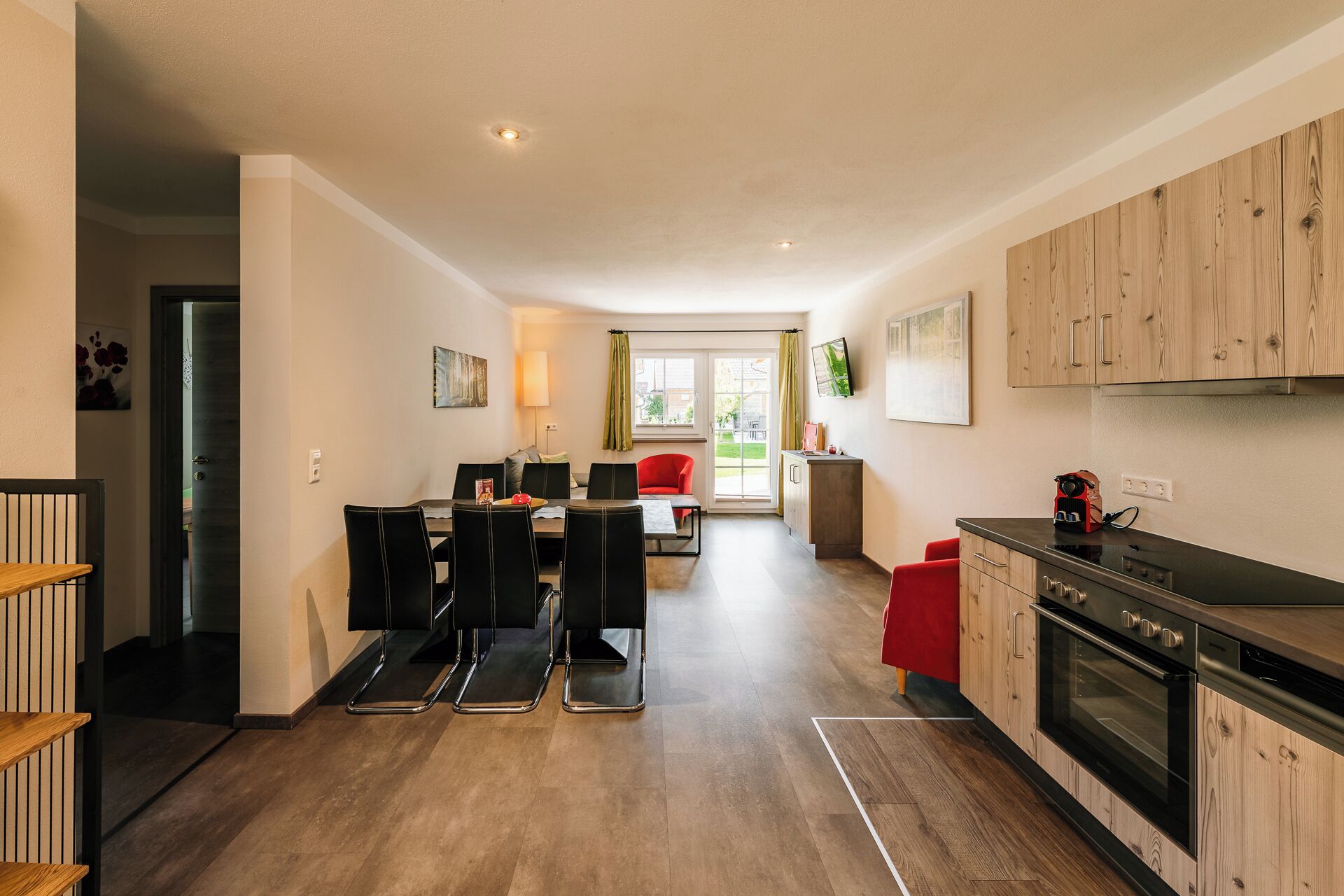 Een moderne keuken met houten kastjes, een inbouwoven en een eethoek met een tafel en stoelen.