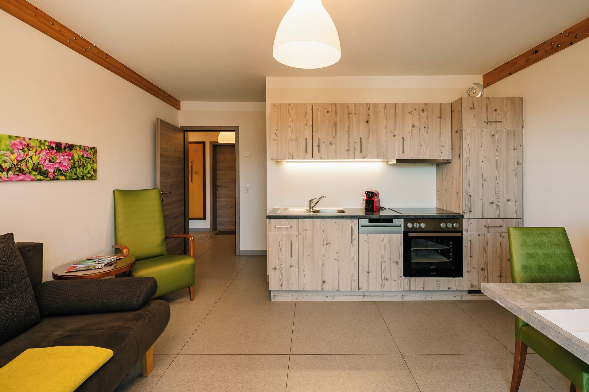 Una cocina moderna con armarios de madera, horno empotrado y comedor con mesa y sillas.