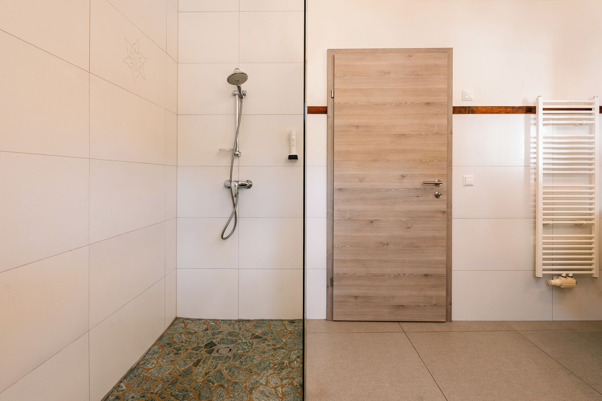 A bathroom with a shower, a wooden door, and a towel rack.