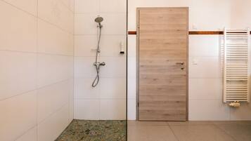 A bathroom with a shower, a wooden door, and a towel rack.
