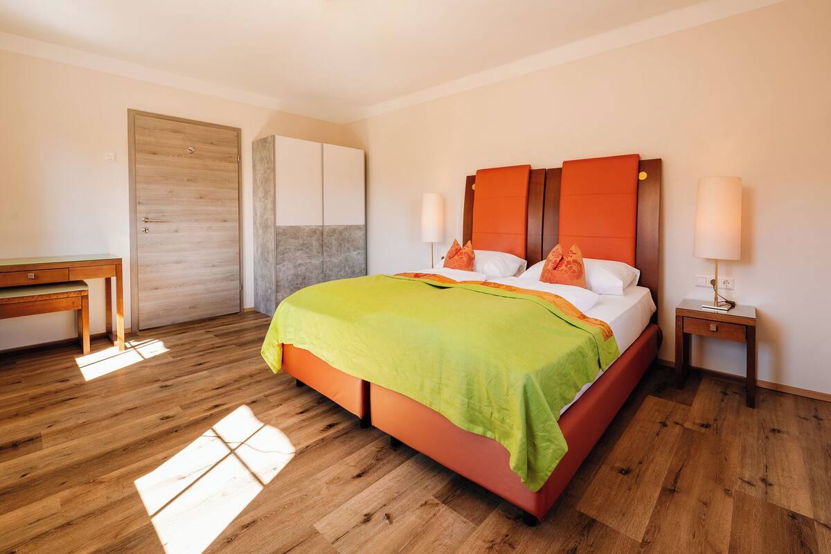 A hotel room with a bed, a desk, a wardrobe, and a nightstand.