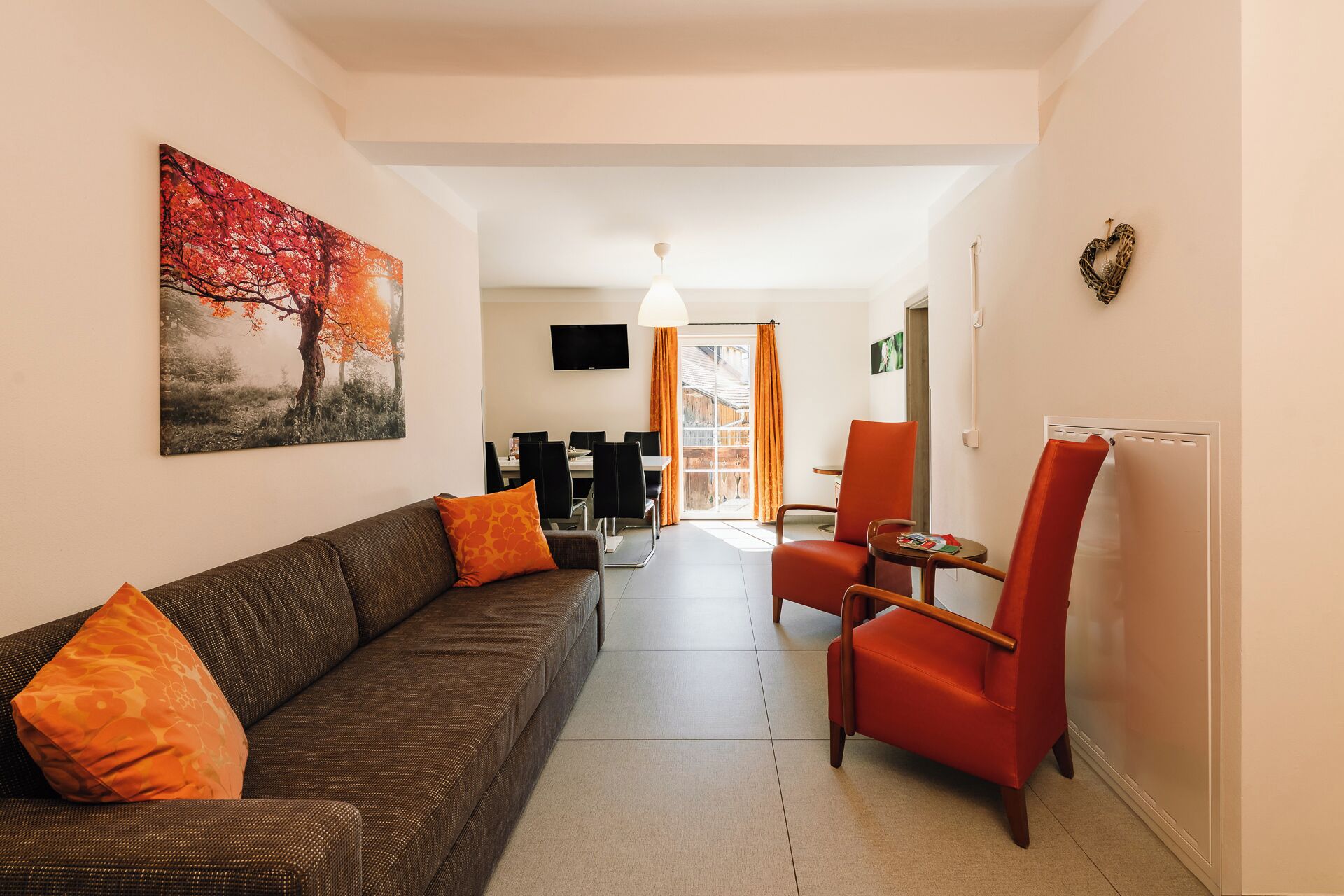 Una sala de estar con un sofá, un sillón rojo y un televisor.