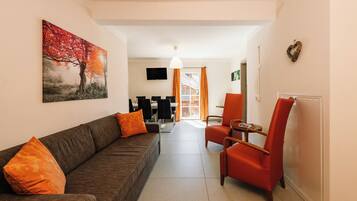 Una sala de estar con un sofá, un sillón rojo y un televisor.