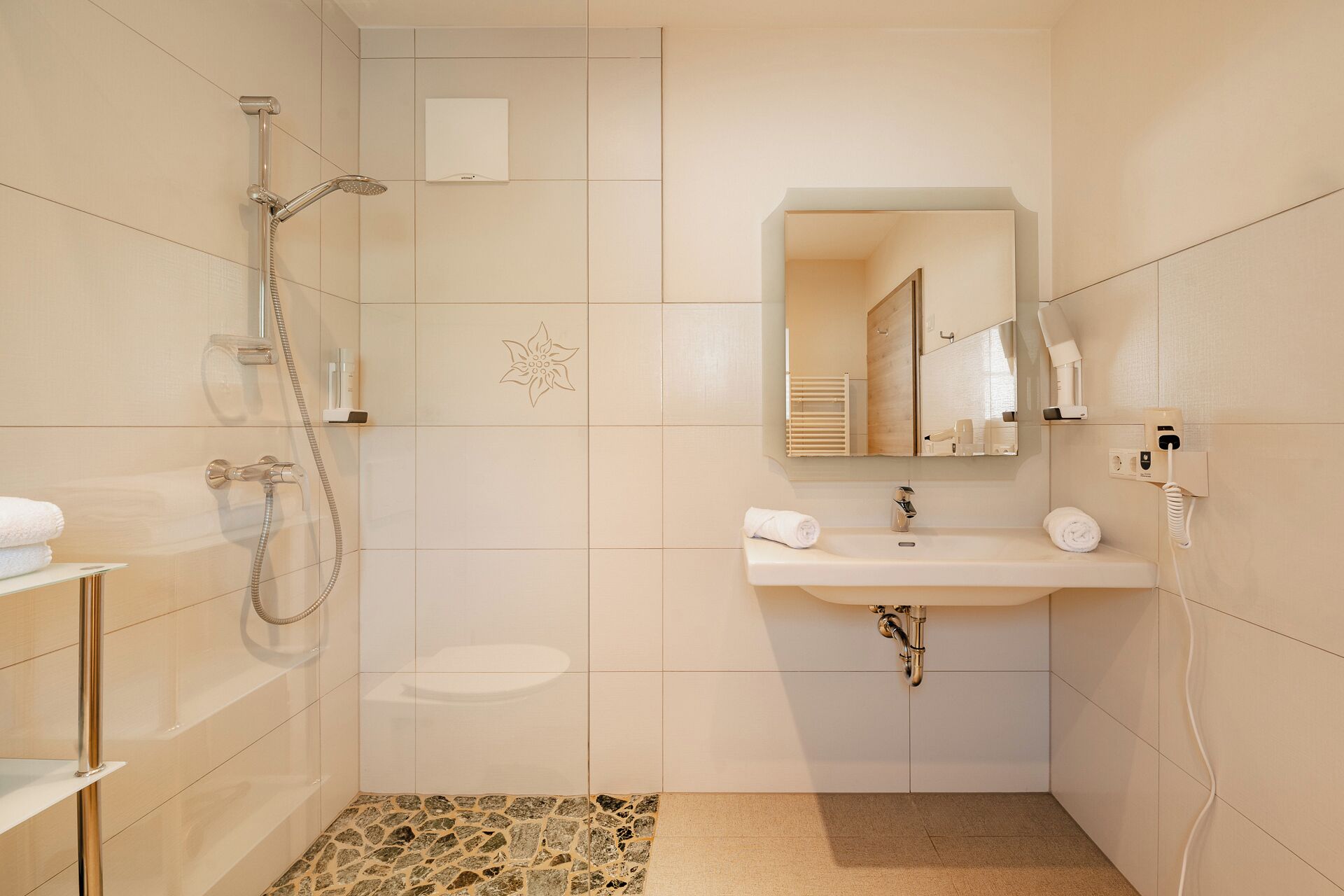 A bathroom with a shower, sink, and mirror.
