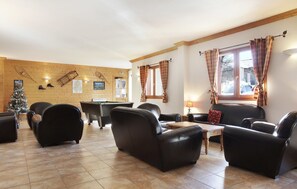 Relax in the lounge area with a pool table, comfortable seating, and sports equipment on display.