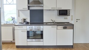 Een moderne keuken met witte kastjes, een inbouwoven, een magnetron en een vaatwasser.