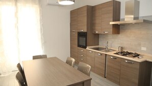 A modern kitchen with wooden cabinets, a built-in oven, a gas stove, and a stainless steel sink. - B&B Mimì (Castelsardo)
