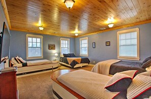 Three beds with unique headboards, large windows, and a cozy atmosphere.