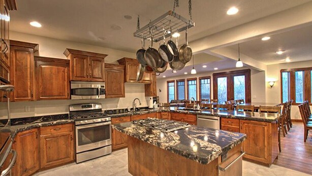 A spacious kitchen with wooden cabinets, stainless steel appliances, and a large granite island.