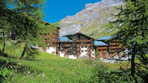 Un hotel de varios pisos con balcones, con montañas al fondo.