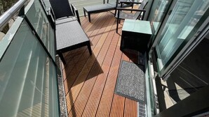 A balcony with a wooden floor, metal railings, and two black chairs. - (311/2) 3- room apartment Ostseeallee - (300) Pier Kühlungsborn (Kühlungsborn)