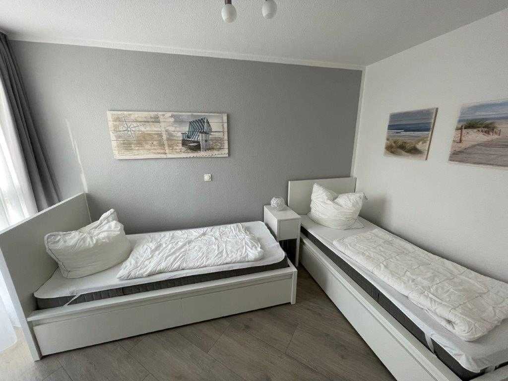 Una habitación pequeña con una cama individual, una mesita de noche y una estantería en la pared.