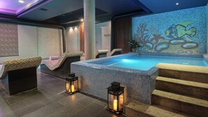 Ein Spa-Bereich mit einem gefliesten Whirlpool, Liegestühlen und Laternen.