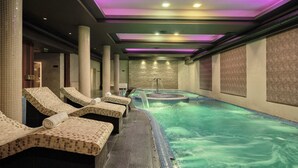 Ein Wellnessbereich mit Whirlpool, Liegestühlen und einer gefliesten Wand.