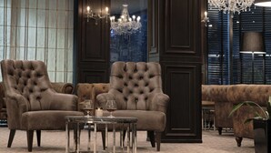 Ein luxuriöses Zimmer mit großem Fenster, einer Kristallleuchtre und einem gepolsterten Sofagarnitur.