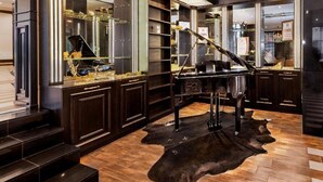Ein luxuriöses Interieur mit einem Flügel, dunklen Holzschränken und einem großen Spiegel, der den Raum wiedergibt.