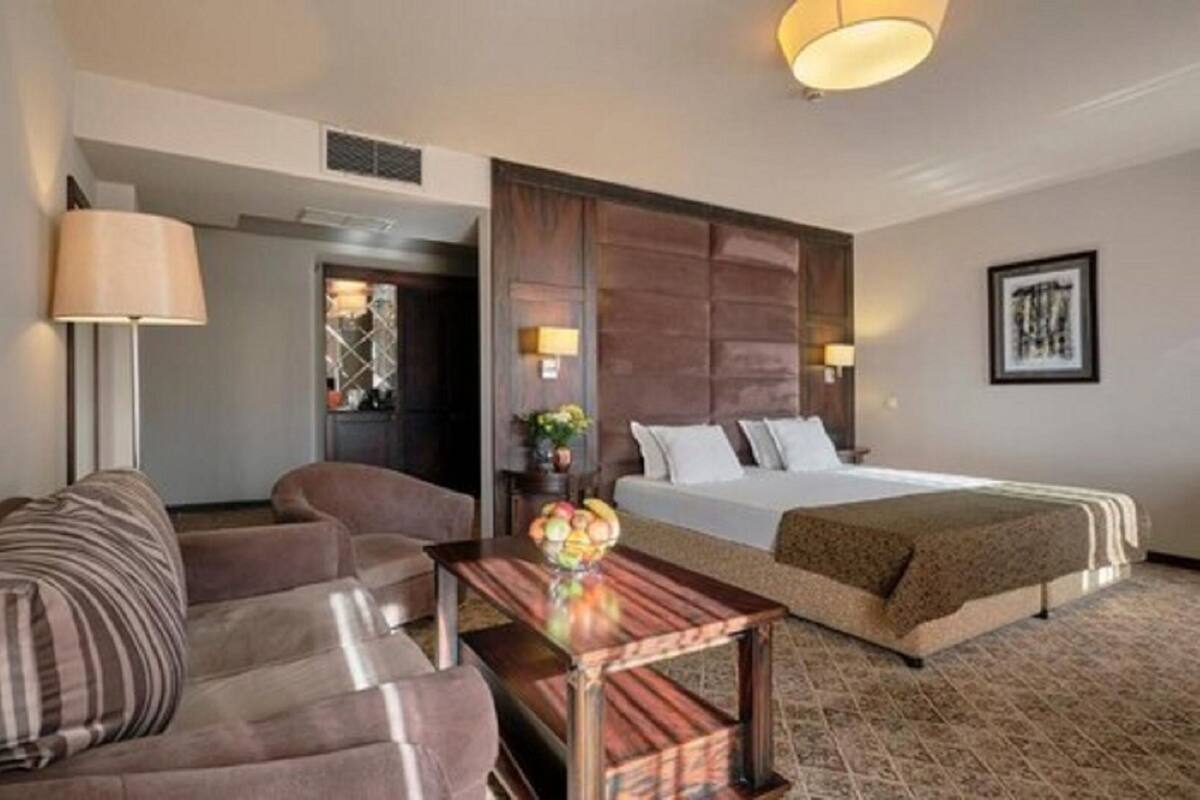 A hotel room with a bed, a sofa, a coffee table, and a lamp.