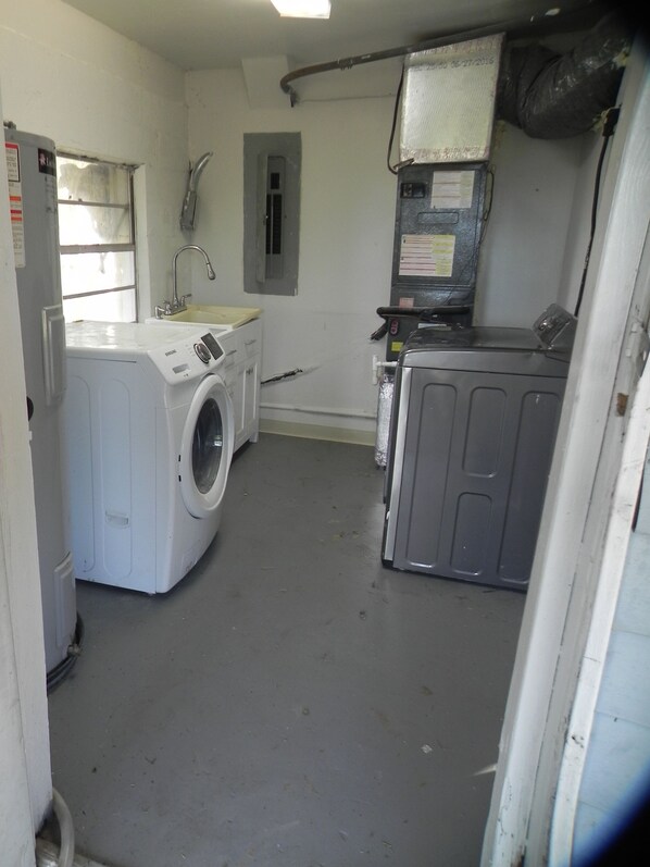 Une buanderie équipée d’un lave-linge, d’un sèche-linge et d’une petite fenêtre.
