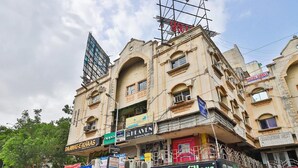 Ein mehrstöckiges Gebäude mit verschiedenen Geschäften im Erdgeschoss, darunter eine Laptop-Reparaturwerkstatt und ein Restaurant namens 'tummy filers'.